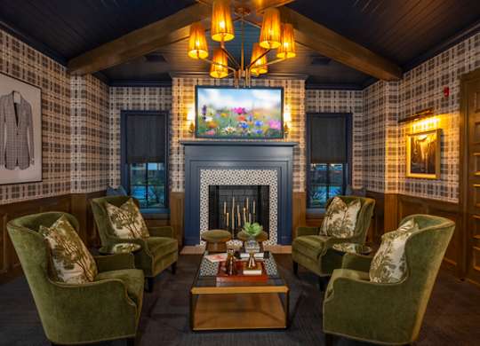 A cozy room with a fireplace and green chairs.