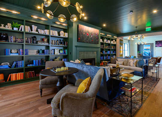 A living room with a dark wood floor and a large painting on the wall.
