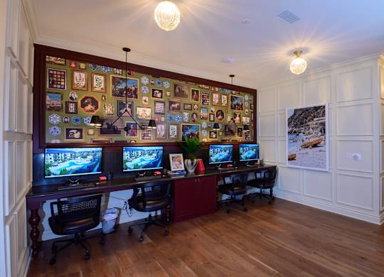A room with a long wall of computer monitors and a desk with two chairs.