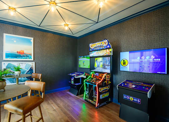 A room with a table, chairs, and a pinball machine.