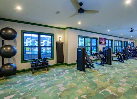 A gym with exercise equipment and a green floor.