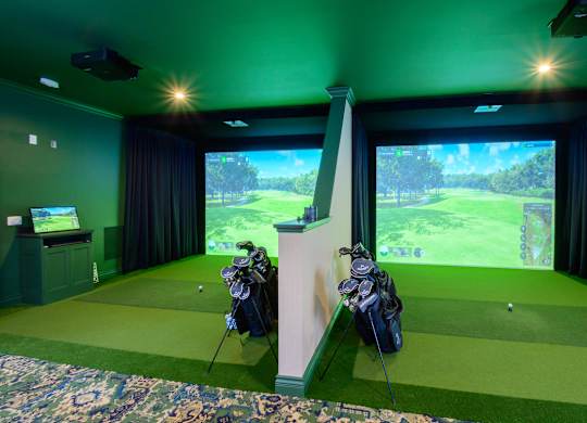 A golf simulator room with a screen showing a golf course.