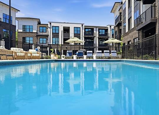 A swimming pool in front of a row of apartment buildings.