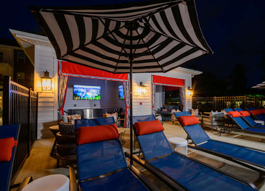 Outdoor lounge area with tv and striped umbrella at Fairmont Apartments, Westerville, OH