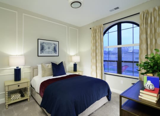 a bedroom with a large window and a bed with a blue comforter  Fairfax, Grandview