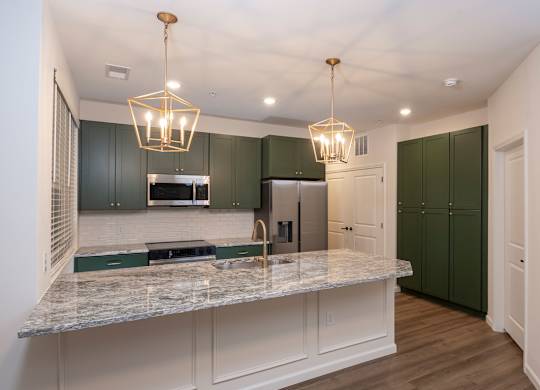 A kitchen with green cabinets and a marble countertop.