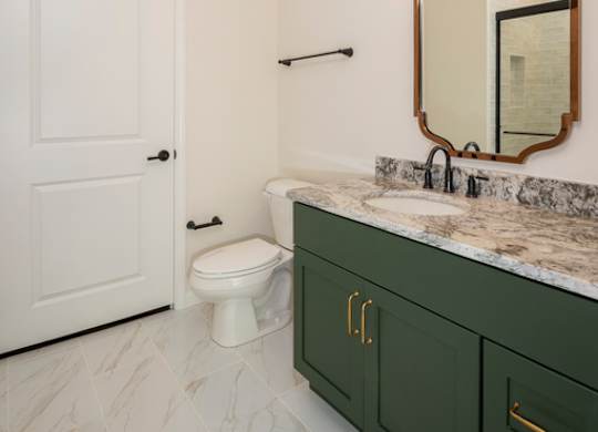 A bathroom with a white toilet and green cabinets.