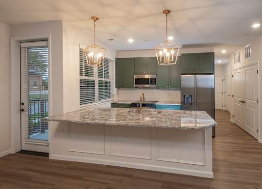 A kitchen with a marble countertop and green cabinets.