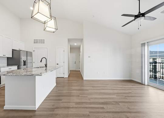 A modern kitchen with a marble countertop and a ceiling fan.