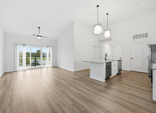 A spacious kitchen with white cabinets and a wooden floor.