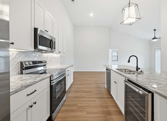 A modern kitchen with a marble countertop and stainless steel appliances.