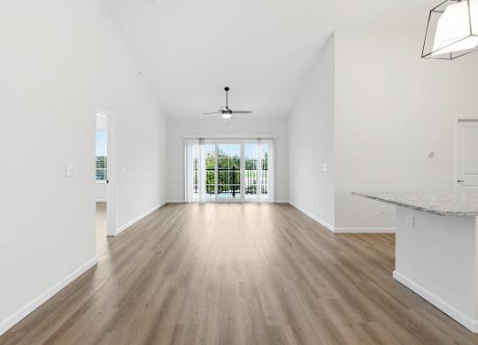 A spacious room with wooden flooring and a ceiling fan.