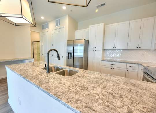 A kitchen with granite countertops and white cabinets.