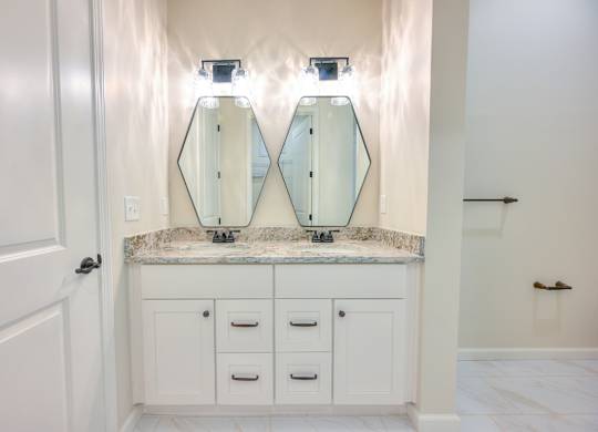 A bathroom with a marble countertop and two mirrors above it.