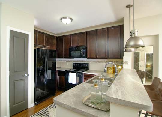 A kitchen with a granite counter top and a black refrigerator.