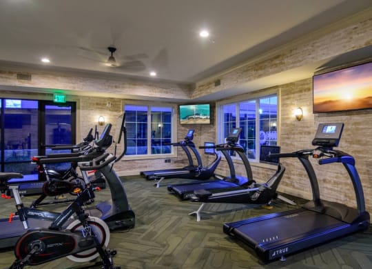 a gym with exercise machines and a tv on the wall