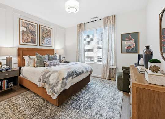 A bedroom with a large bed and a rug on the floor.