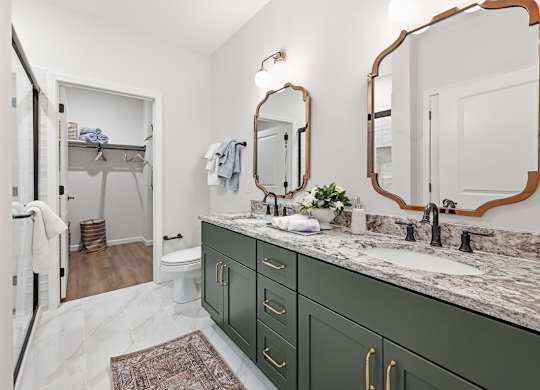 A bathroom with green cabinets and a marble countertop.