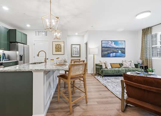 A kitchen with green cabinets and a white island with a wooden chair.