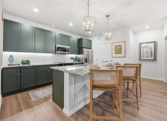 A kitchen with green cabinets and a white island.