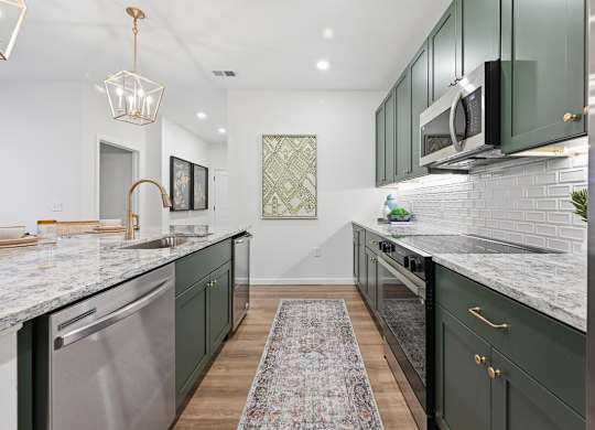 A kitchen with green cabinets and a marble countertop.