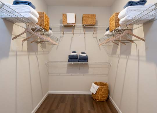 A laundry room with clothes on shelves and a basket on the floor.