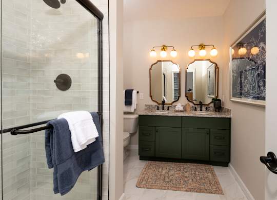 A bathroom with a glass shower door and a green vanity.