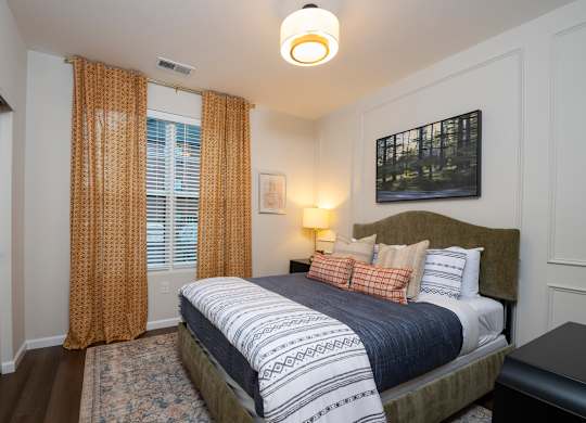 A bedroom with a large bed and a painting on the wall.