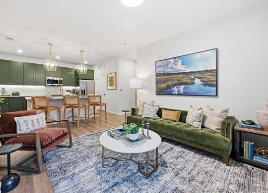 A living room with a green couch, a coffee table, and a painting on the wall.
