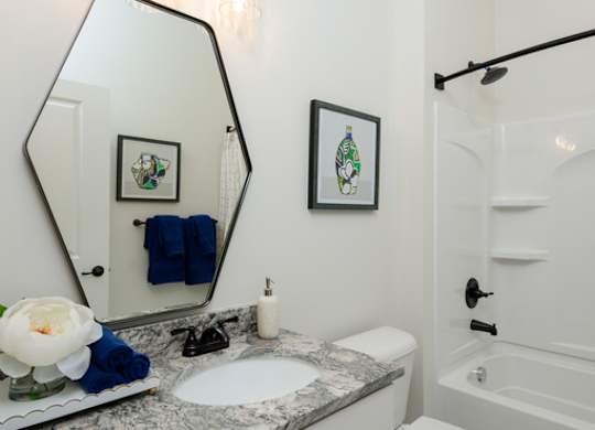A bathroom with a white toilet and a marble counter top.