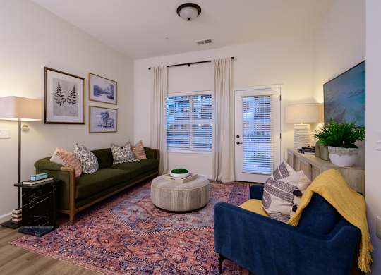 A living room with a blue couch and a rug.