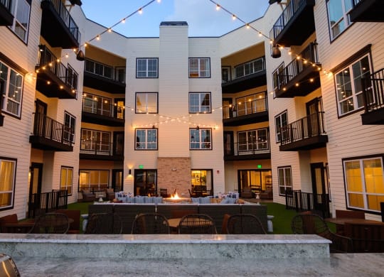 an outdoor patio with a firepit and string lights at the flats at big tex apartments in at Essex, Ohio, 43212