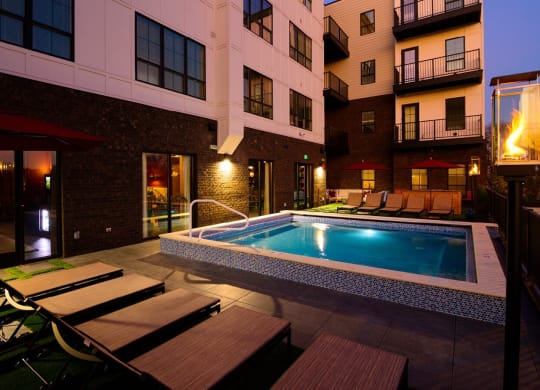 a pool with lounge chairs and umbrellas in front of an apartment building at Fairfax, Grandview, 43212
