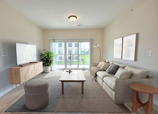 A living room with a grey sofa, a wooden coffee table, a grey ottoman, a wooden side table, a flat screen TV, a potted plant, and a window with a view of a building outside.