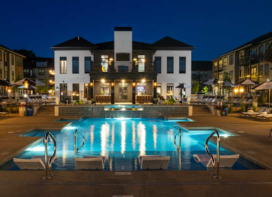 A large white building with a pool in front of it at night.