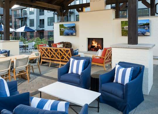 A cozy outdoor seating area with blue chairs and a fireplace.