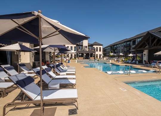 A pool area with sun loungers and umbrellas.