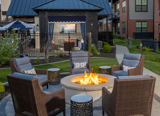 A fire pit surrounded by chairs in a garden setting.