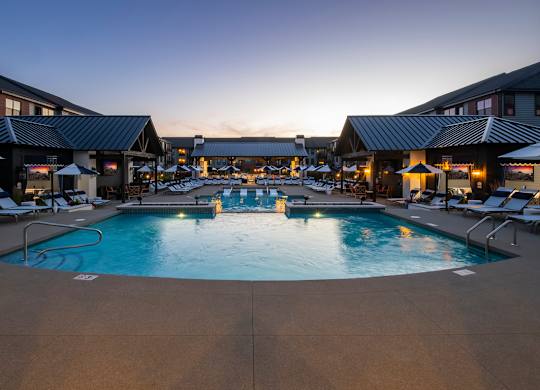 A large outdoor swimming pool surrounded by lounge chairs and umbrellas.