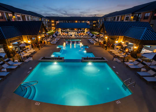 A large outdoor swimming pool surrounded by lounge chairs and umbrellas.