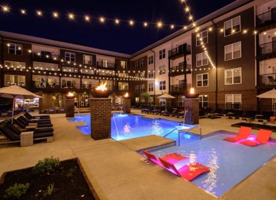 the pool is lit up at night at the apartments