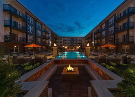 an outdoor pool with a fire pit at night