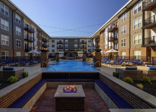 an outdoor pool with a fire pit in front of an apartment building