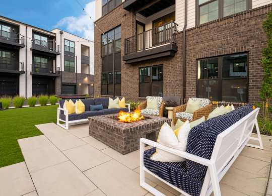 A patio with a fire pit and chairs.
