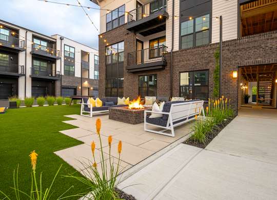 A modern outdoor seating area with a fire pit and chairs.