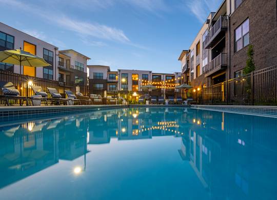 A pool in front of apartment buildings at dusk.