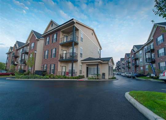 A row of apartment buildings with a car parked in front of the first one.