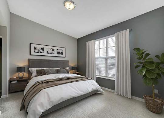 A bedroom with a large bed and a potted plant.