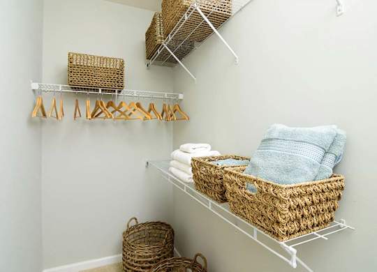 A white shelf with baskets and towels on it.