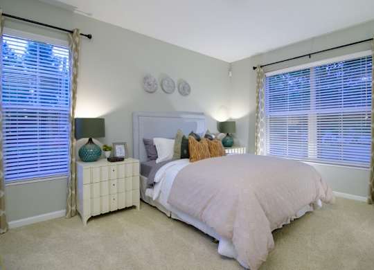 A bedroom with a bed, nightstand, and window with curtains.